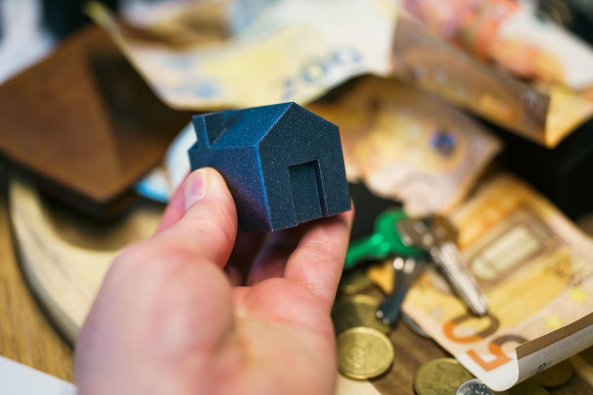 A small piggy bank sitting next to a set of house keys on a table.