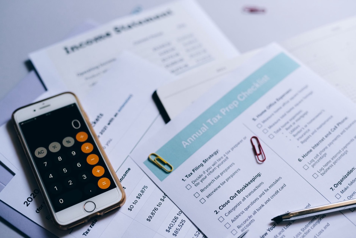 Calculadora e documentos de papel sobre uma mesa de madeira.