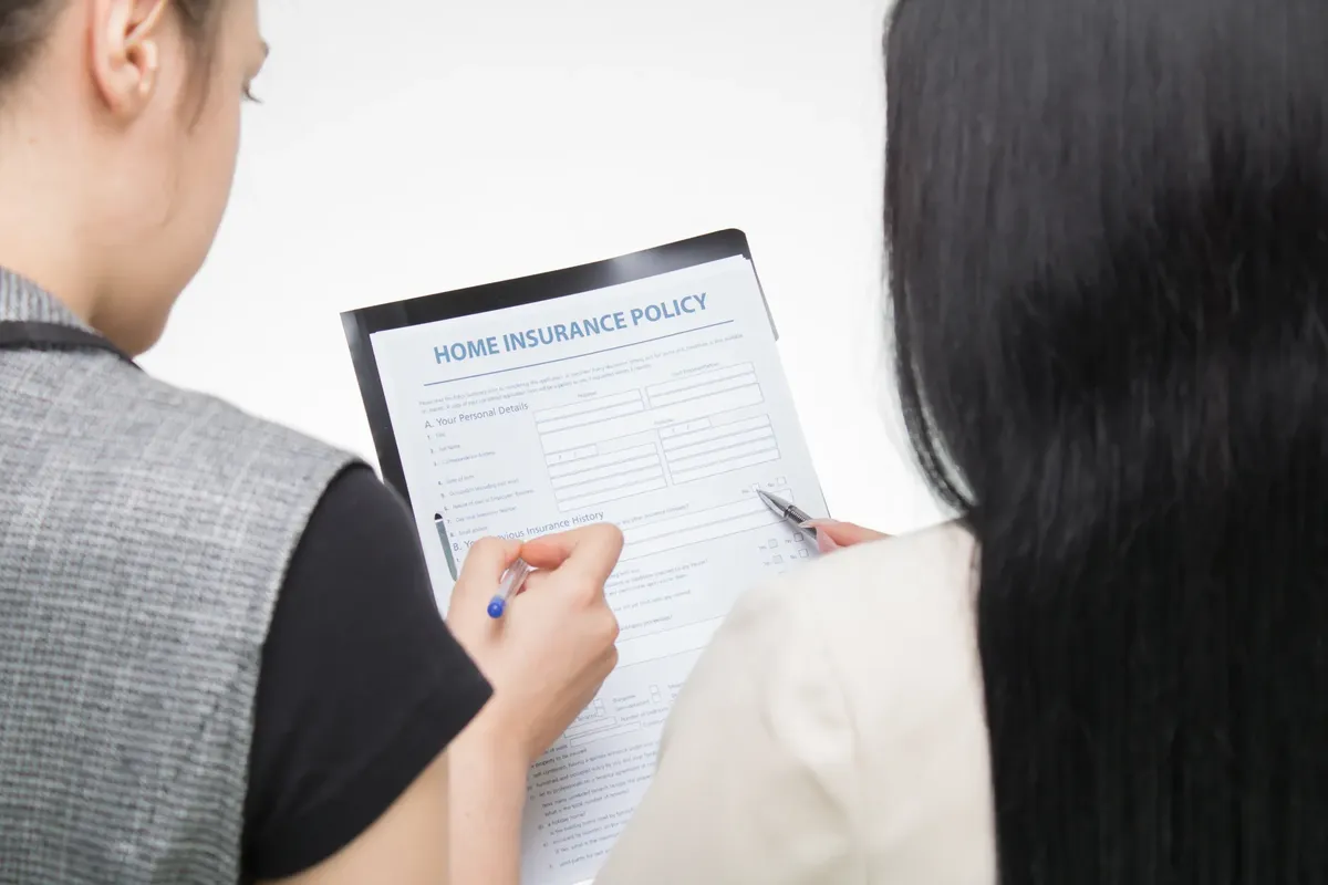 Two women examining home insurance policy form, focused on details.